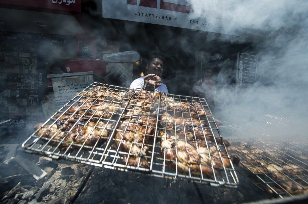 Cozinheiro assa frangos na brasa em restaurante do Cairo, Egito