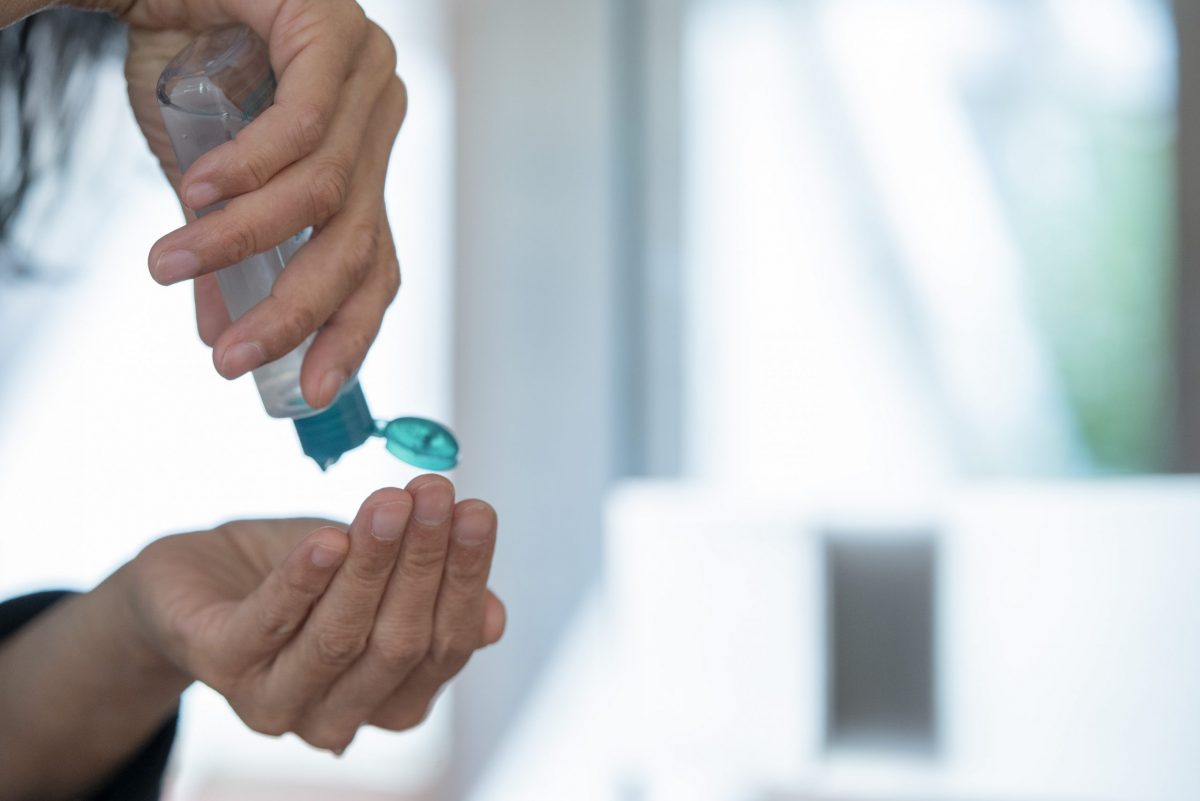Man's hands applying alcohol sanitizer gel