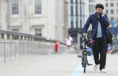 Businessman with smart phone walking bicycle