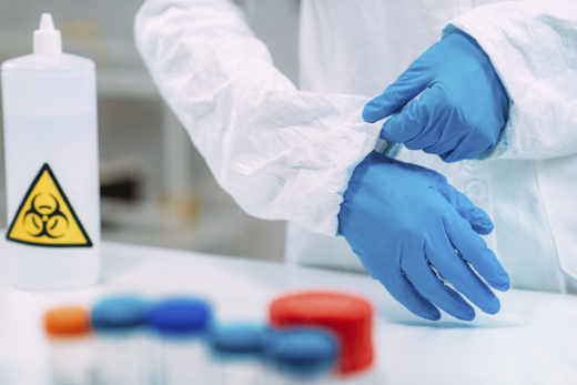 Lab technician putting on protective clothing