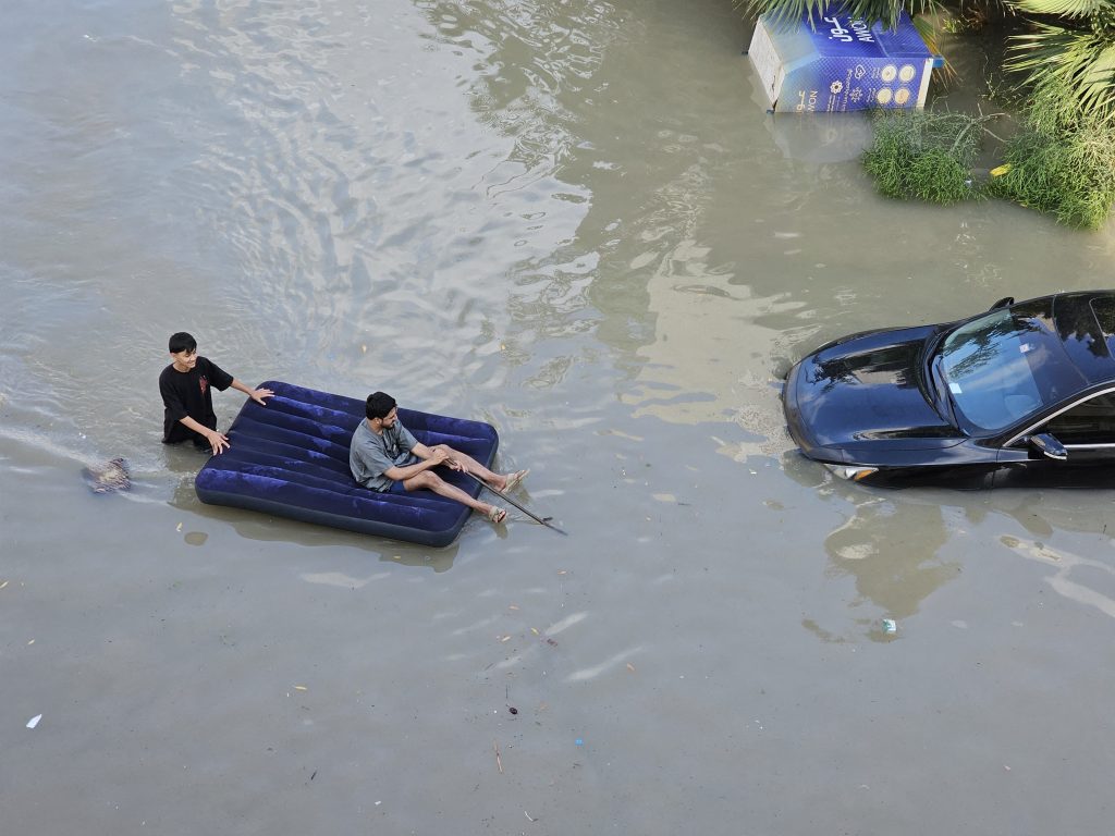 Homem em colchão inflável navegando na inundação em Dubai