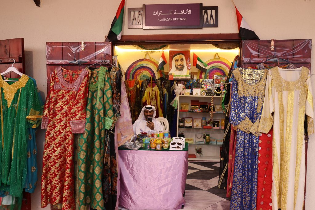 Um vendedor dos Emirados que vende vestidos em sua loja durante um festival anual de patrimônio em Al-Ain
