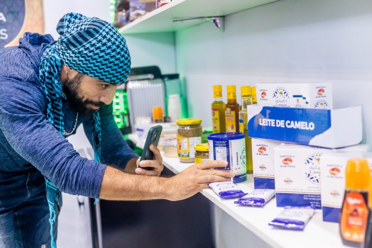 Actor Kaysar Dadour photographs camel milk in the stand of Taybe
