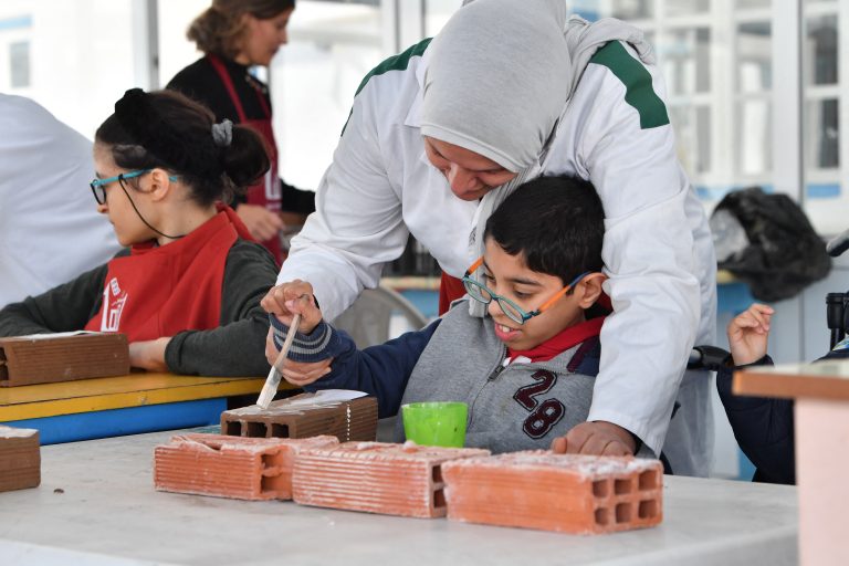 (FILES) A group of young people with disabilities participate in the creation of a collaborative work of art at an institute that offers educational, artistic and social programs in La Marsa, a suburb of Tunis, on February 22, 2024. - In the old medina of Tunis, a wall installation titled "1001 Bricks" showcases the talents of "invisible" creators, including art students, people with disabilities and school dropouts. (Photo by FETHI BELAID / AFP)