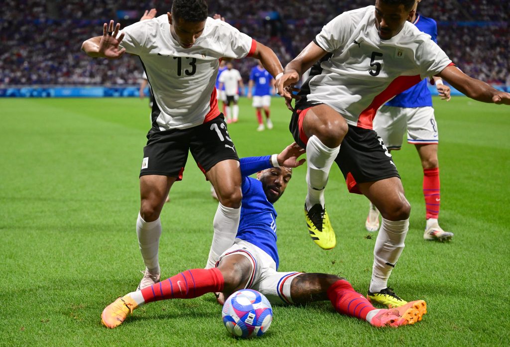 France's forward #10 Alexandre Lacazette fights for the ball with Egypt's defender #13 Karim El Debes and Egypt's defender #05 Hossam Abdelmaguid during the men's semi-final football match between France and Egypt during the Paris 2024 Olympic Games at the Lyon Stadium in Lyon on August 5, 2024. (Photo by Olivier CHASSIGNOLE / AFP)