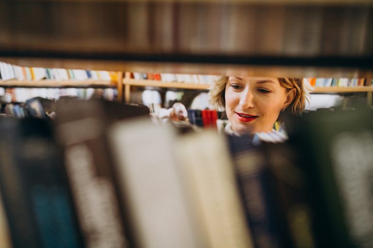 Young woman choosing book at the library