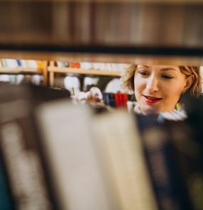 Young woman choosing book at the library