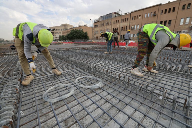Iraqi labourers work on a bridge under construction on Abu Nawas Street in Baghdad on November 26, 2024. (Photo by AHMAD AL-RUBAYE / AFP)