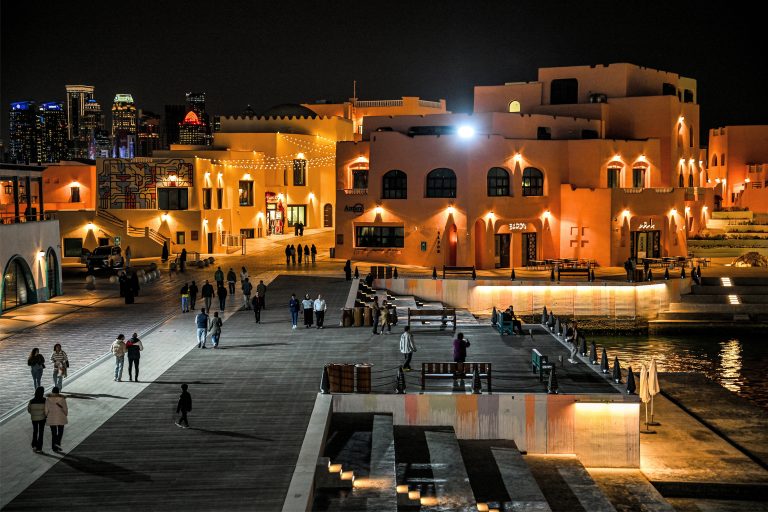 People walk at the Mina district in Doha, Qatar, a popular spot for visitors, on February 5, 2024. (Photo by Hector RETAMAL / AFP)