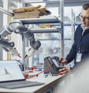 Engineer moving robotic arm with control panel