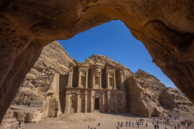 Ad Deir, The Monastery in Petra, Jordan seen in a frame from a cave. Deir is also known as ad-Dayr and el-Deir, a monumental building carved out of rock in the ancient Jordanian city of Petra. The Deir was carved out of rock in the mid-first century AD. The ancient attraction is one of the most iconic monuments in the Petra Archaeological Park and thousands of tourists visit the area in the desert mountains. The Monastery is located high in the hills northwest of the Petra city center, the second most commonly visited monument in Petra, after the Khazneh or "Treasury". The huge façade, the inner chamber and the other structures next to it or in the wider area around the Deir probably originally served a complex religious purpose, and was possibly repurposed as a church in the Byzantine period. Petra was originally known to its inhabitants as Raqmu or Raq?m? is a historic and archaeological city in southern Jordan enlisted in UNESCO World Heritage Site. Petra, Jordan on December 2022 (Photo by Nicolas Economou/NurPhoto) (Photo by Nicolas Economou / NurPhoto / NurPhoto via AFP)