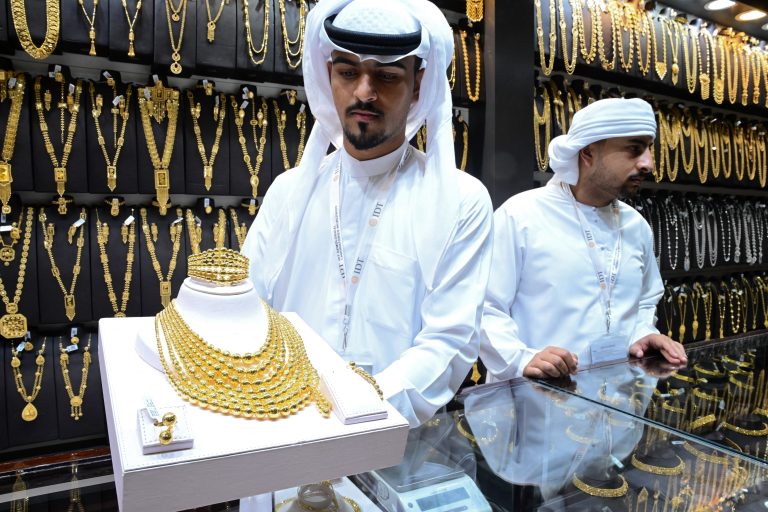 A jeweler shows a golden necklace and other accessories during the Watch and Jewelry Middle East Show in the Sharjah, United Arab Emirates.