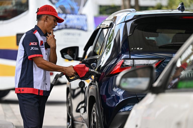 An employee fills up a car at at a gas station amid rising petrol prices in Quezon City, Metro Manila on March 9, 2026. The price of the main US benchmark for oil surged more than 30 percent on March 9, 2026 over concerns that the Middle East war could create prolonged supply disruptions. (Photo by Jam STA ROSA / AFP)
