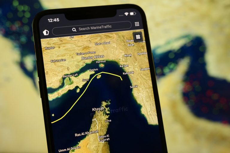 Smartphone exibe o app MarineTraffic com navio passando por Estreito de Ormuz após acordo de cessar-fogo