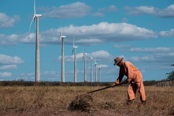 Agricultor trabalha próximo a parque de turbinas eólicas no Rio Grande do Norte: fontes de energia renovável ajudam a reduzir impactos do preço do petróleo